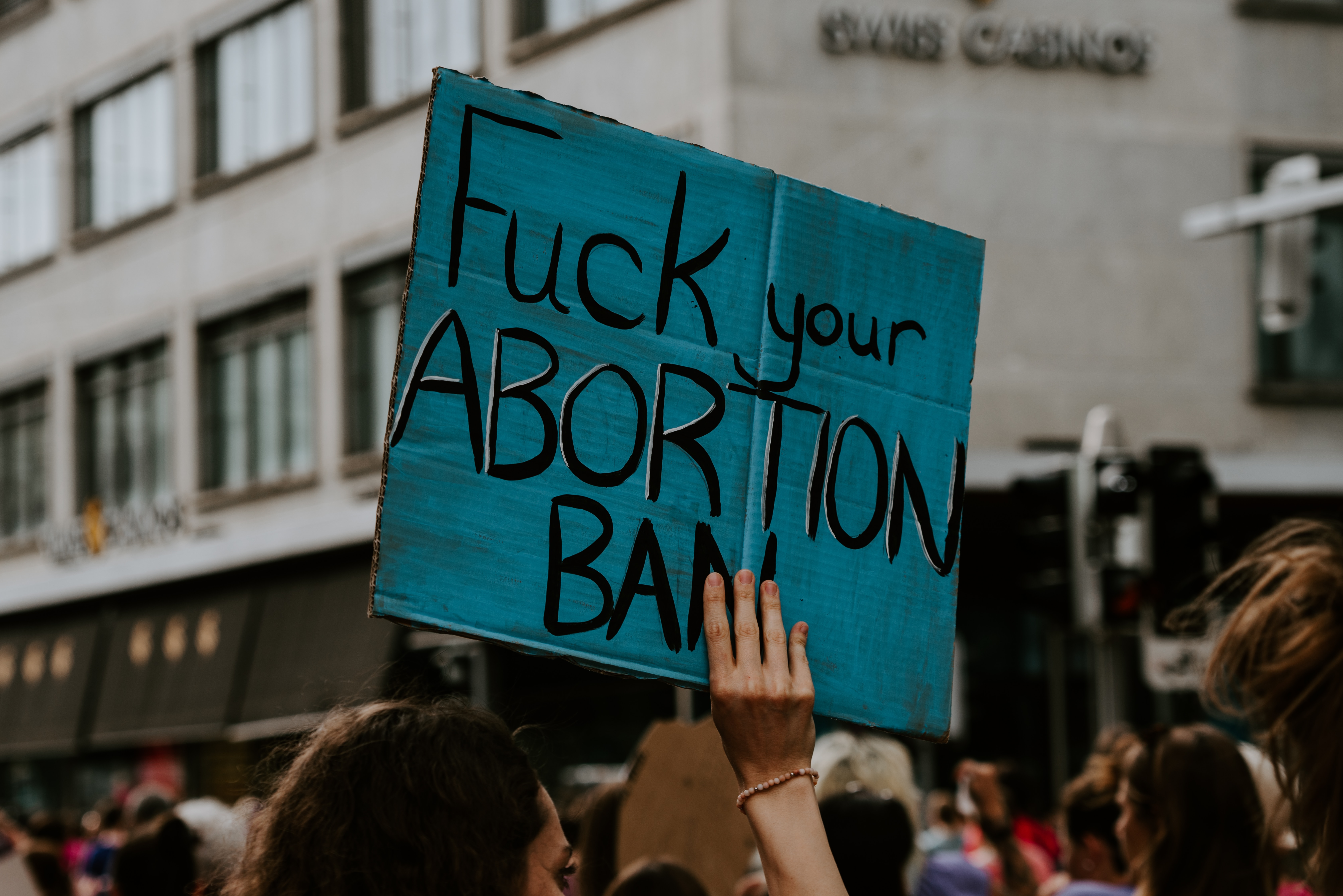 fuck your abortion ban someone holding a poster on a demonstration with the words "fuck your abortion ban" written on it