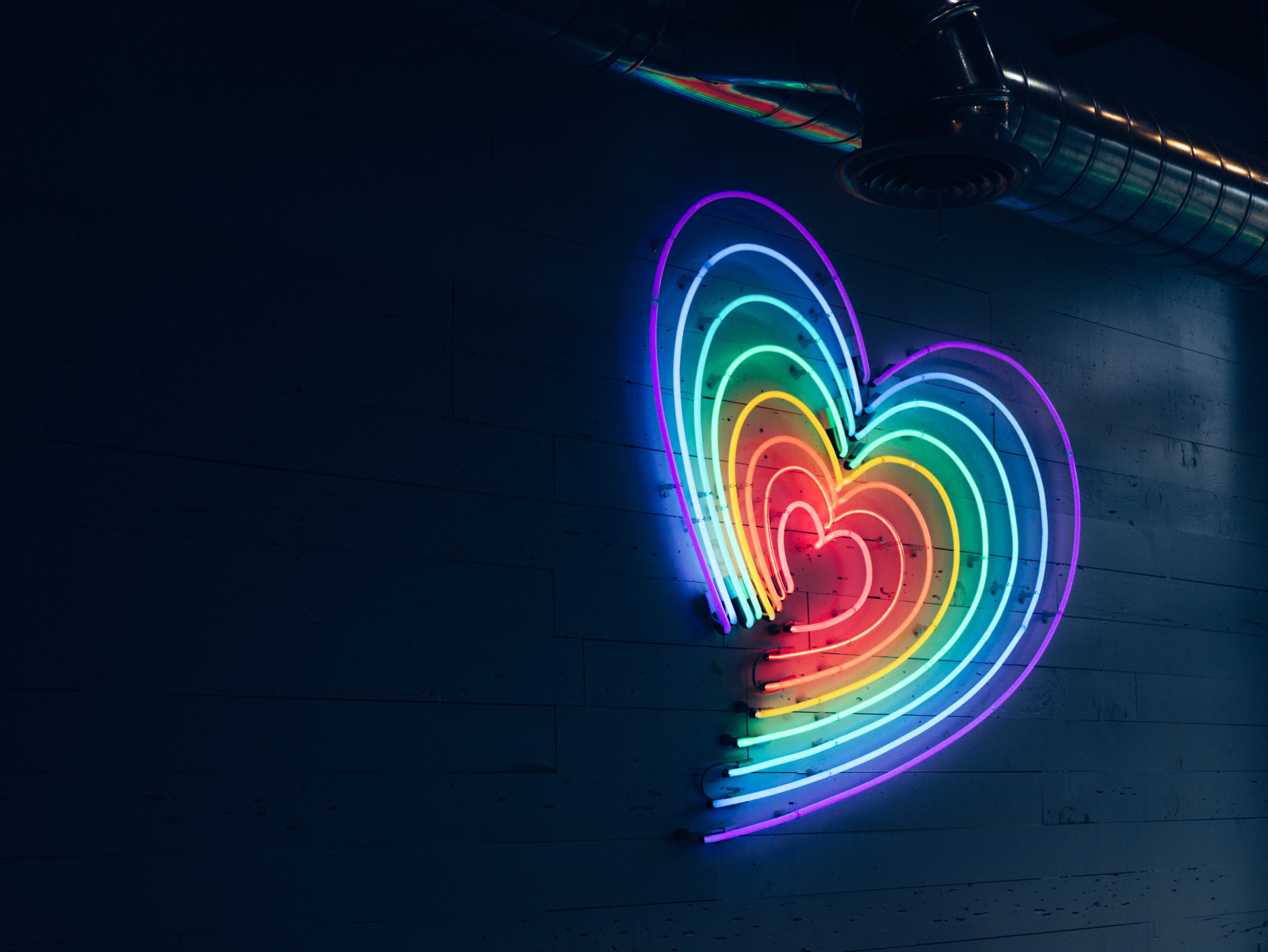 Ein Neonschild in Herzform mit Regenbogenfarben