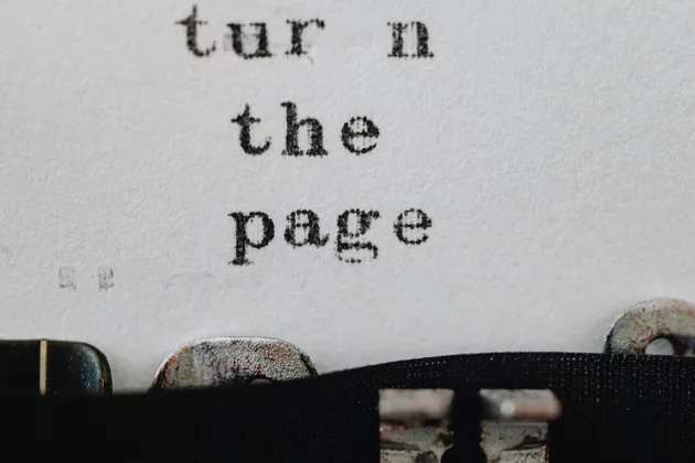 Das Blatt in einer Schreibmaschine zeigt den Text: Turn the Page. Blätter um, auf Deutsch.