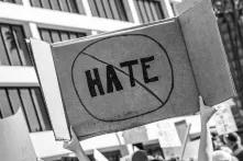 someone holding a poster at a demonstration with the word "hate" crossed out on it