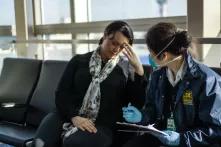 A public health officer is asking questions to a sick traveller at an airport.