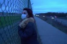 women with hygiene mask standing at a fence