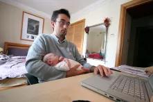 dad at home working on computer and holding baby