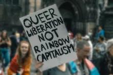 Eine Person hält ein Schild auf dem "queer liberation not rainbow capitalism" steht