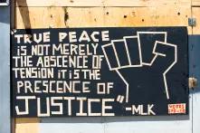 Zitat MLK "True peace is not merely the abscence of tension it is the presence of justice" auf einer Wand