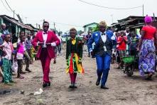 Drei Personen in bunten Anzügen gehen durch Straße