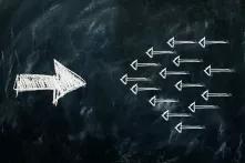 Schwarze Tafel mit weißer Kreide: Links ein großer nach rechts gerichteter Pfeil gegen mehrere nach link gerichtete Pfeile