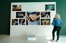 Person steht vor großer Leinwand auf der mehrere Bilder zu Eizellspende befestigt sind