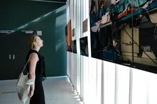 Person steht vor einem Vorhang dem Bilder der Ausstellung befestigt sind