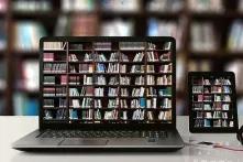 Foto eines Laptops und Tablets vor einem Bücherregal, der Bildschirm des Laptops und des Tablets zeigen das Bücherregal