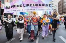 Auf dem Bild sind bunt angezogene Personen, die ein Plakat auf der Pride halten mit der Aufschrift "Be pride like Ukraine". Das Bild wurde in Berlin aufgenommen.