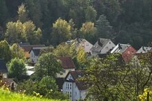 Am Hang eines Berges liegen moderne Einfamilienhäuser. Eines hat einen geschmacklosen Erker. Das Licht ist sanft und angenehm.