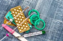 verschiedene Verhütungsmittel liegen auf dem Tisch: Spirale, Kondome, Pille, Thermometer