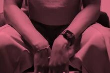 Junge schlanke Arme stützen sich auf dazugehörige Knie. Die Person lehnt sich vermutlich zur betrachtenden Person.