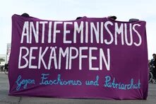 Ein lilafarbenes Transparent wird von Demonstrierenden gehalten. Darauf steht: "Antifeminismus bekämpfen. Gegen Faschismus und Patriarchat."