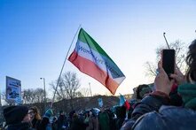 Eine grün-weiß-rote Flagge des Irans mit dem Schriftzug "Women Life Freedom"