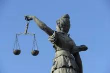 Foto der Rückseite einer Skulptur der Justizia mit Waagschalen in der linken Hand