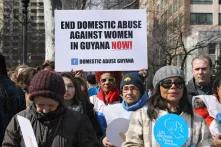 Teilnehmerinnen der Demo zum 08.03.2015 in new York - Plakat mit Aufschrift :"end domestic abuse against women in guyana now"