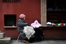 a cloaked woman selling knitwear in the street