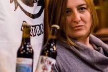 Leila Šeper vor dem Logo ihrer Brauerei mit zwei Bierflaschen