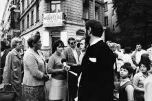 Eine Gruppe Menschen steht vor einem Haus mit einem Banner "Widerstand gegen Massenkündigungen" 