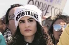 Eine Frau mit einer Mütze steht in einer Demonstration. Auf ihrer Mütze ist gestickt: Women's place is in the resistance