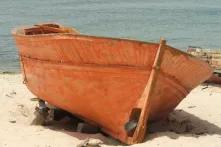 Ein oranges Boot liegt an einem Strand