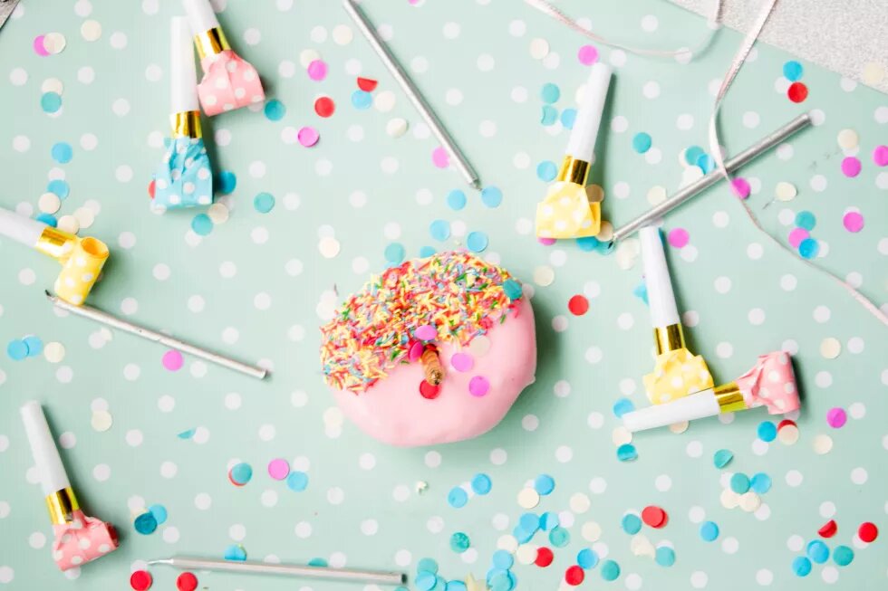 Donut mit Kerze umringt von Partytröten Donut mit Kerze umringt von Partytröten