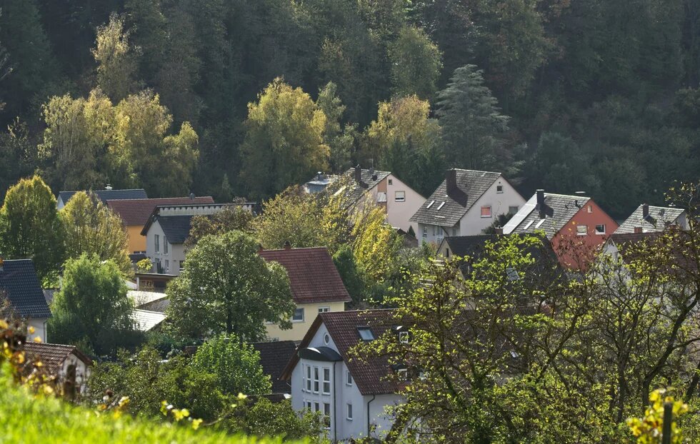 Antifeminismus und Provinzialität. Zur autoritären Abwähr von Emanzipation. Am Hang eines Berges liegen moderne Einfamilienhäuser. Eines hat einen geschmacklosen Erker. Das Licht ist sanft und angenehm.