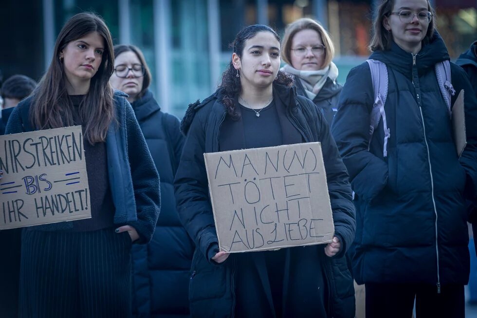 Eine Gruppe von Frauen protestiert in Köln gegen Femizide. Zu sehen ist eine Fraue mit einem Protestschild mit der Aufschrift: Man(n) tötet nicht aus Liebe