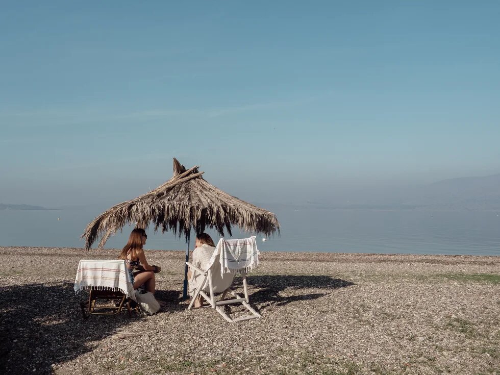 zwei Frauen unter einem Schirm am Strand