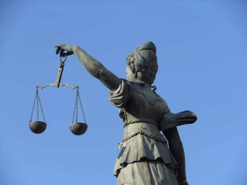 Scales of Justice Foto der Rückseite einer Skulptur der Justizia mit Waagschalen in der linken Hand