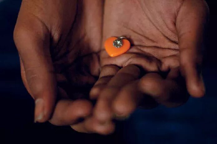 Teilcover Broschüre "Fluchtgrund: Sexuelle OrIentIerung und GeschlechtsIdentItät" Geöffnete Handflächen, die ein kleines organes Schmuckherz halten