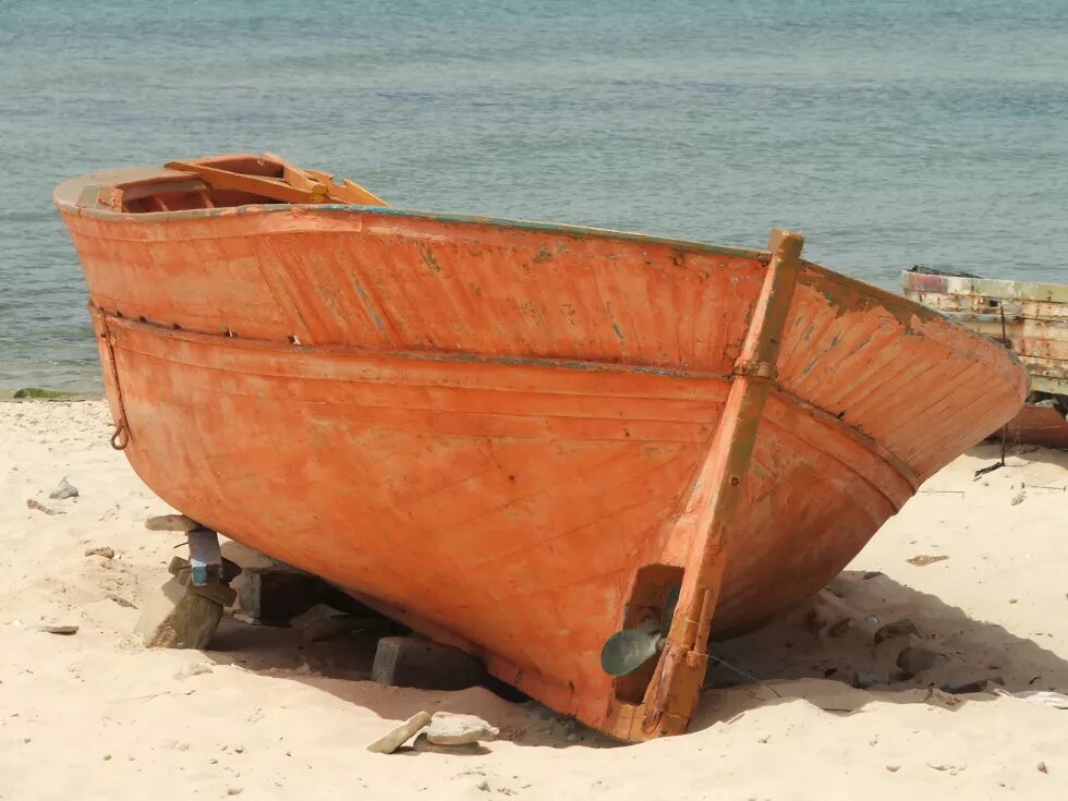 Ein oranges Boot liegt an einem Strand