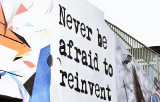 grafitti on wall "never be afraid to reinvent"