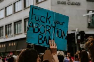 fuck your abortion ban someone holding a poster on a demonstration with the words "fuck your abortion ban" written on it