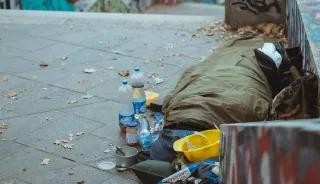 homeless person sleeping in sleeping bag on the ground