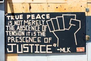 Zitat MLK "True peace is not merely the abscence of tension it is the presence of justice" auf einer Wand