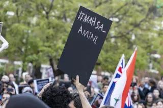 Protests with black sign and caption "#Mahsa Amini"