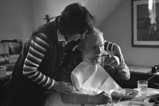 Pflege ist als Care-Aufgabe historisch betrachtet schon immer eine weiblich geprägte Domäne ältere Frau hilft älterem Mann beim Essen