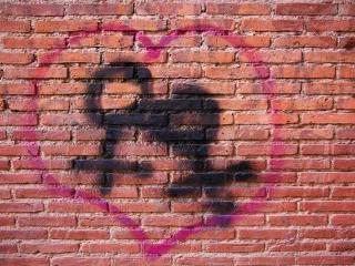 women in love Ziegelsteinmauer, daraus ein Graffitti: rosa Herz mit zwei Venussymbolen