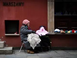 a cloaked woman selling knitwear in the street