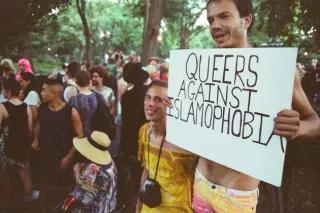 menschenmenge eine person hält ein schild: queers against islamophobia