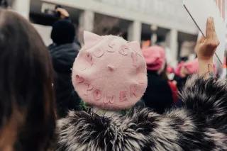 Foto einer Person mit einer rosanen Mütze, auf der steht: Pussy grabs back.