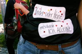 Foto einer Person, die auf ihren Bauch Slipeinlagen geklebt hat. Auf den Slipeinlagen ist mit Hand geschrieben: "Kinder oder keine. Entscheide ich alleine."