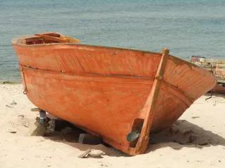 Ein oranges Boot liegt an einem Strand