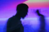Zwei Silhouetten vor buntem Hintergrund/Licht.