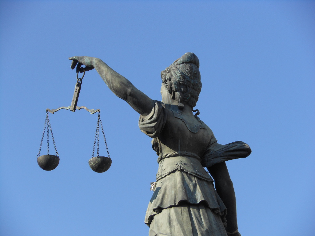 Scales of Justice Foto der Rückseite einer Skulptur der Justizia mit Waagschalen in der linken Hand