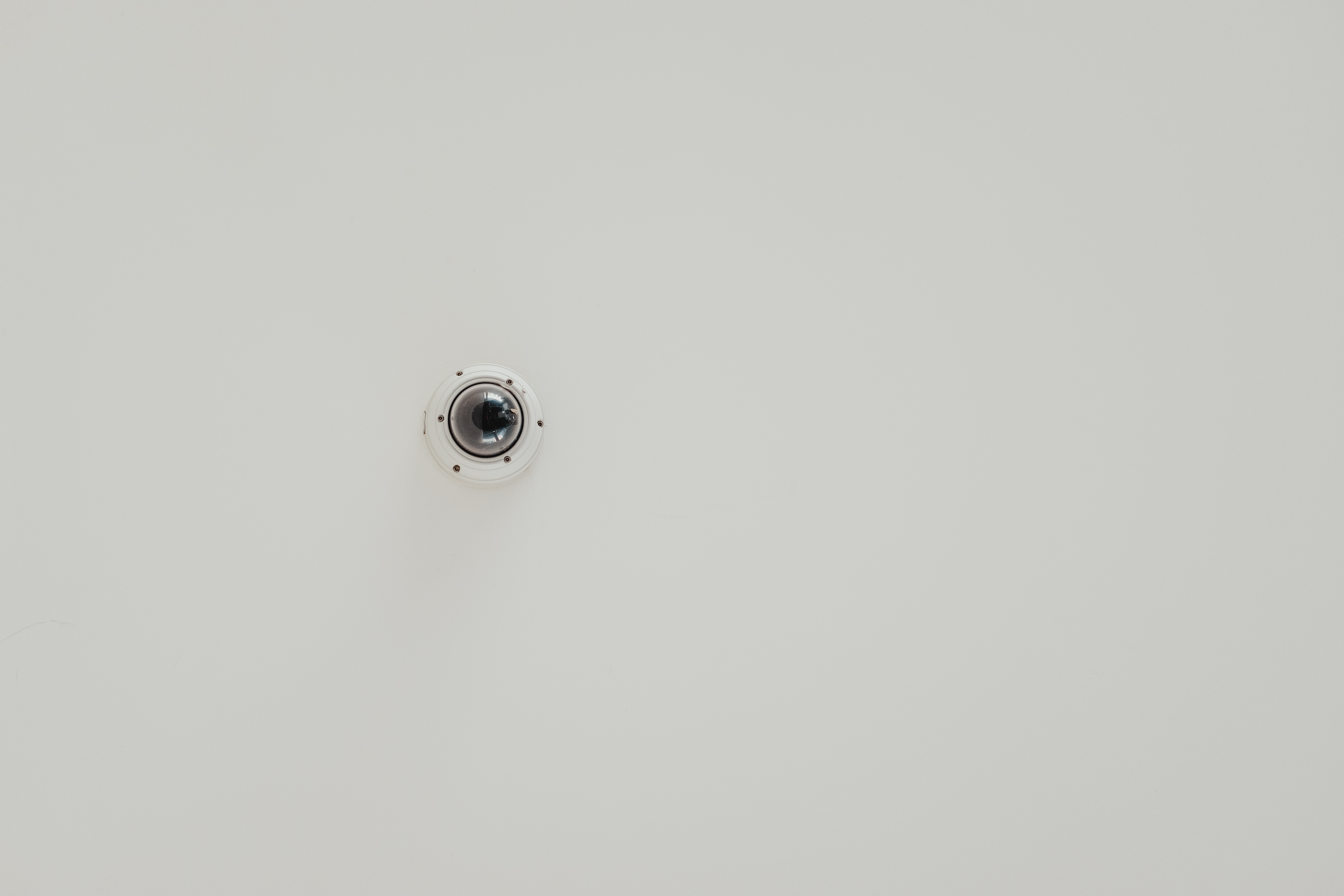 Surveillance camera on white wall.